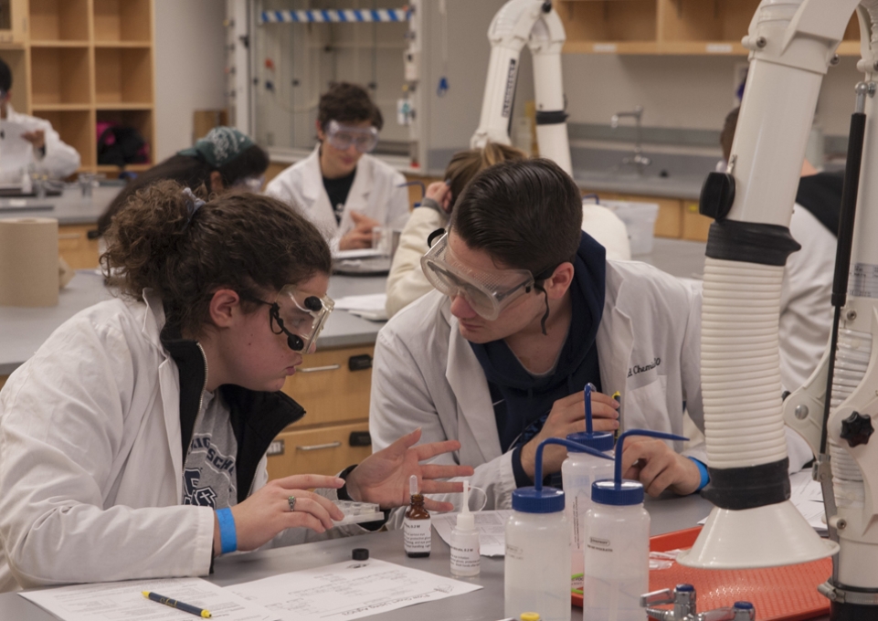 Two students in lab coats sitting and talking