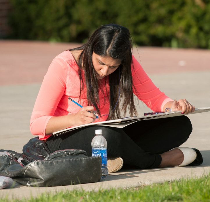 Student drawing in a sketch book outside