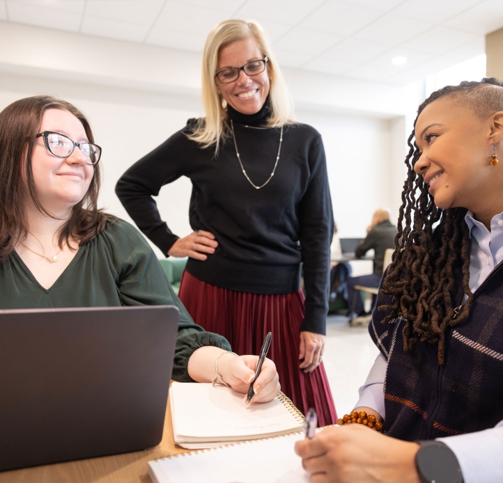 Three grad students writing in notebooks