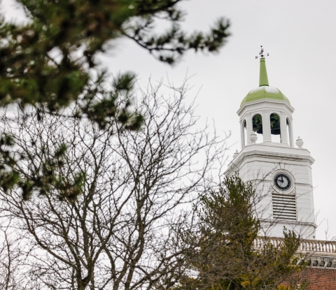A view of the Rockwell Hall clocktower with a tree in front