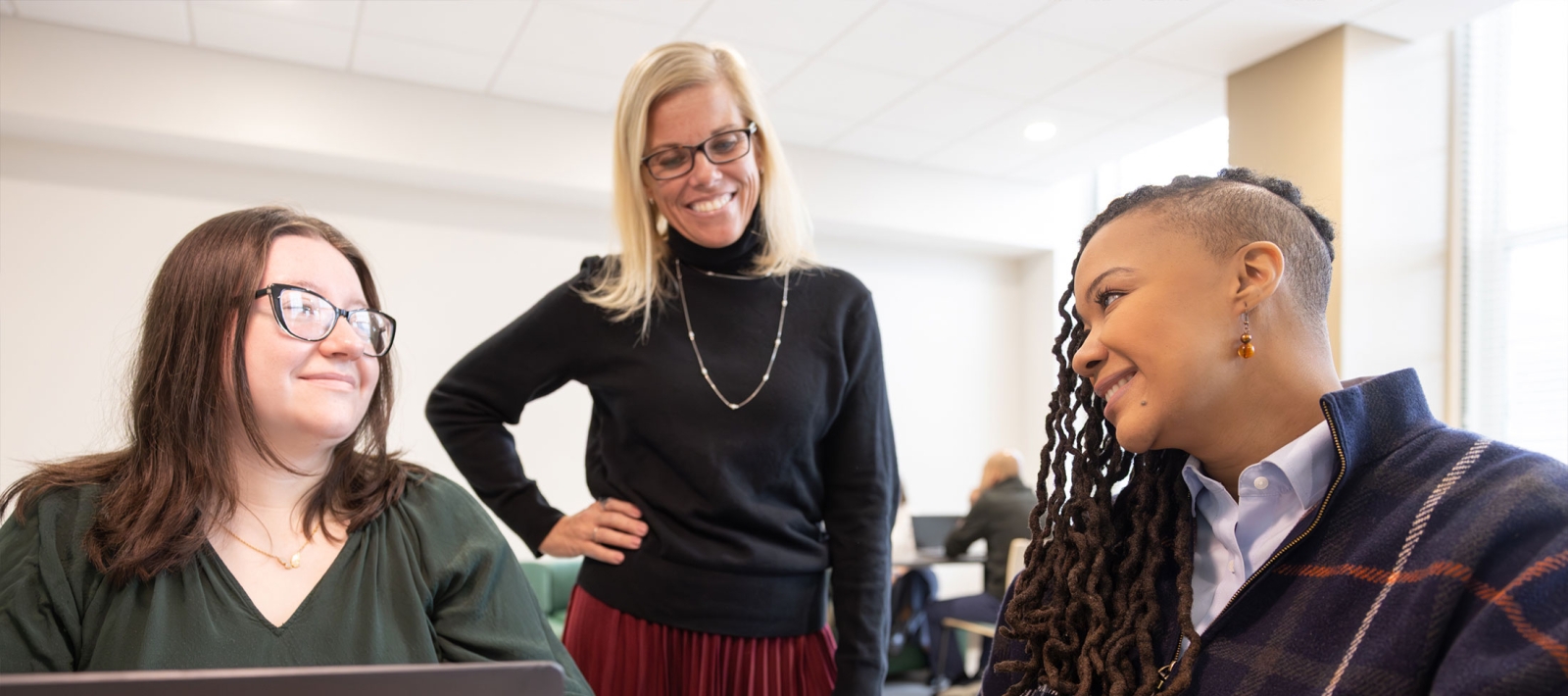 Three grad students writing in notebooks